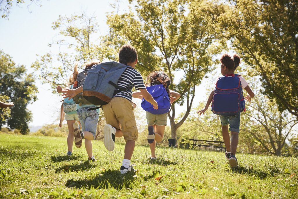 Five school kids running in a field, back view, close up